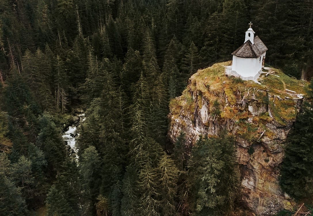 Kirche auf einem Felsen inmitten von Bäumen im Turtmanntal, Wallis.