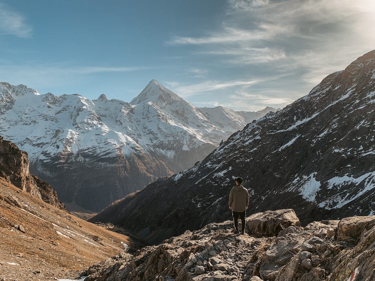 Bertal steht mit dem Rücken zur Kamera vor den schneebedeckten Bergen im Lötschental