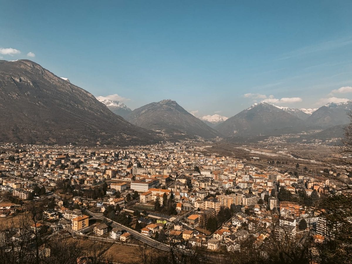 Aussicht über Domodossola vom Sacro Monte aus. Im Hintergrund sind hohe Berge zu erkennen.